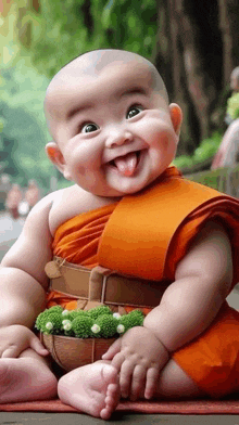 a baby dressed as a monk is sitting on the ground and smiling with his tongue hanging out .