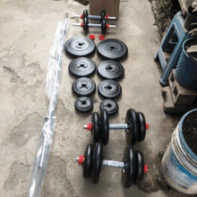 a set of dumbbells and barbells are laid out on a concrete surface