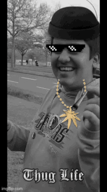 a man wearing sunglasses and a necklace with a marijuana leaf and the words thug life on the bottom