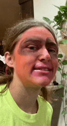 a girl in a neon yellow shirt has red paint on her face