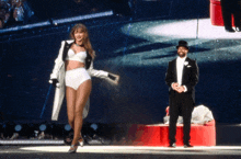 a man in a tuxedo stands next to a woman in a white bra