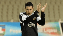 a soccer player wearing a shirt that says azersin is clapping his hands