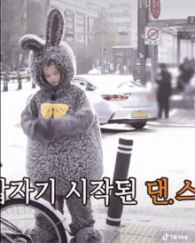 a woman in a bunny costume is standing next to a bicycle .