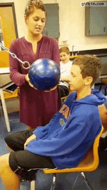 a girl holding a bowling ball next to a boy wearing a blue sweatshirt that says ' da ' on it