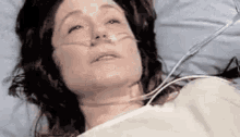 a woman is laying in a hospital bed with an oxygen tube in her nose .