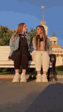 two girls are sitting on a bench with one wearing a black shirt that says ' a ' on it