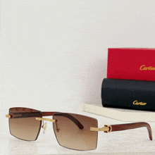 a pair of cartier sunglasses sits next to a red box