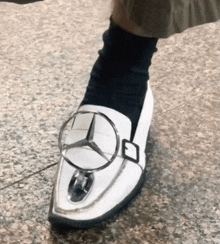 a person wearing a pair of shoes with a mercedes logo on them