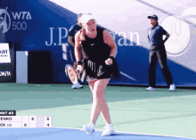 a woman in a black skirt stands on a tennis court in front of a sign that says wta 500 on it