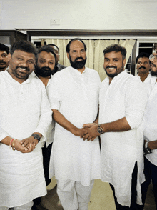 a group of men wearing white shirts are posing for a photo