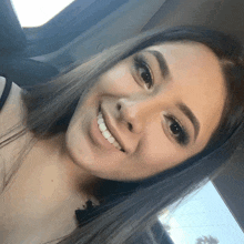 a woman is smiling and looking at the camera while sitting in a car