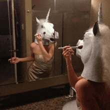 a woman in a unicorn mask applying makeup in front of a mirror