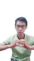 a man wearing glasses and a green shirt makes a heart shape with his hands