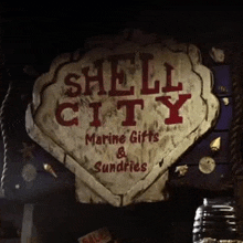 a sign for shell city marine gifts and sundries is hanging on a rope .