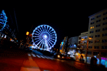 a large ferris wheel is lit up at night