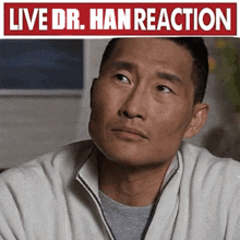 a man in a white jacket is sitting in front of a sign that says `` live dr . han reaction '' .