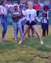 a woman is dancing in front of a crowd of people while wearing a pink shirt .