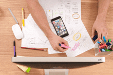 a person is writing on a piece of paper with a cell phone on top of the paper