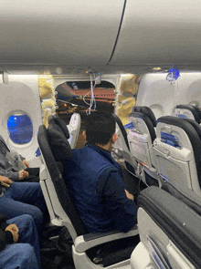 a man sits in a seat on an airplane with a blue sign that says united