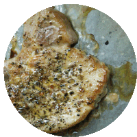 a close up of a pork chop with sauce and pepper on it