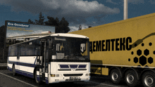 a white and blue bus is parked next to a yellow trailer that says цементекс