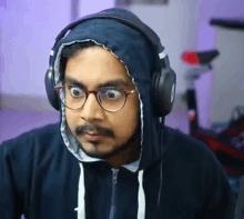 a man wearing headphones and a hoodie is making a surprised face .