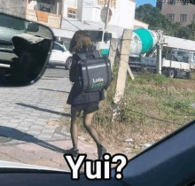 a girl in a school uniform is walking down the street with a backpack on her back .