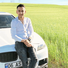 a man sitting on the hood of a white car with a license plate that says 06 as