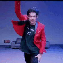 a man in a red jacket is dancing on a stage in a living room .