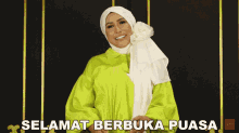 a woman wearing a hijab and a green shirt with the words selamat berbuka puasa below her