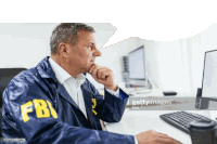 a man in a fbi jacket is looking at a computer screen .