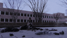 a man sits on the ground in front of a large building with a lot of electronics on the ground in front of him