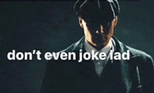 a man in a suit and hat with the words " don 't even joke lad " behind him