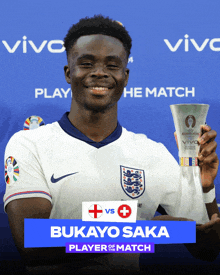 a man holding a trophy with the name bukayo saka on it