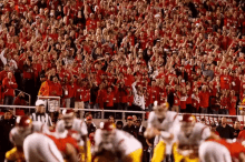 a football game is being played in front of a crowd that is wearing red and white jerseys with the word texas on them