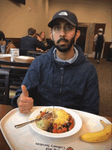 a man sitting at a table with a plate of food and a tray that says culinary services on it