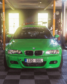 a green bmw with a license plate that says 330 bbl is parked in a garage