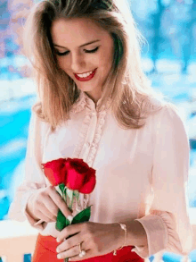 a woman is holding a bouquet of red roses and smiling .