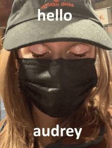 a woman wearing a mask and a hat that says hello audrey on it