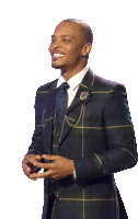 a man in a plaid suit is smiling and holding his hands together