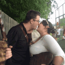 a man and a woman kissing in front of a fence with a sign that says ' a ' on it