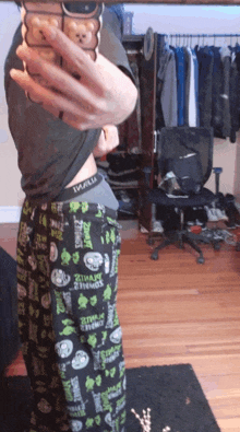 a man taking a picture of himself in a closet wearing pajama pants that say zombies on them