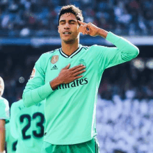 a soccer player wearing a green emirates jersey holds his hand to his chest