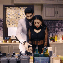 a man and a woman are cooking in a kitchen and the woman is wearing a black top