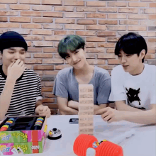 three young men are playing a game with a stack of jenga blocks on the table