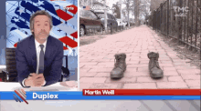 a man in a suit and tie is sitting at a desk with a pair of boots on the ground in front of a washington sign