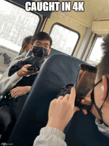 a man taking a picture of another man on a bus with a caption that says caught in 4k