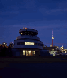 a control tower is lit up at night with a toronto skyline in the background