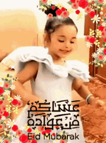 a little girl in a white dress is dancing in front of flowers and the words eid mubarak