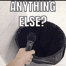 a person is holding a microphone in front of a trash can that says `` anything else ? ''